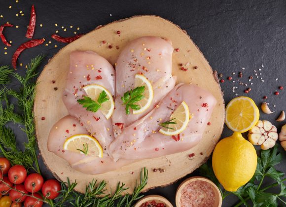 Advantages of a Meat-Based Diet - These Might Surprise You! raw chicken fillet with garlic, pepper and rosemary on wooden on chopping board. fresh fillet. fresh chicken meat, chicken fillet with spices at black stone table. top view with copy space.